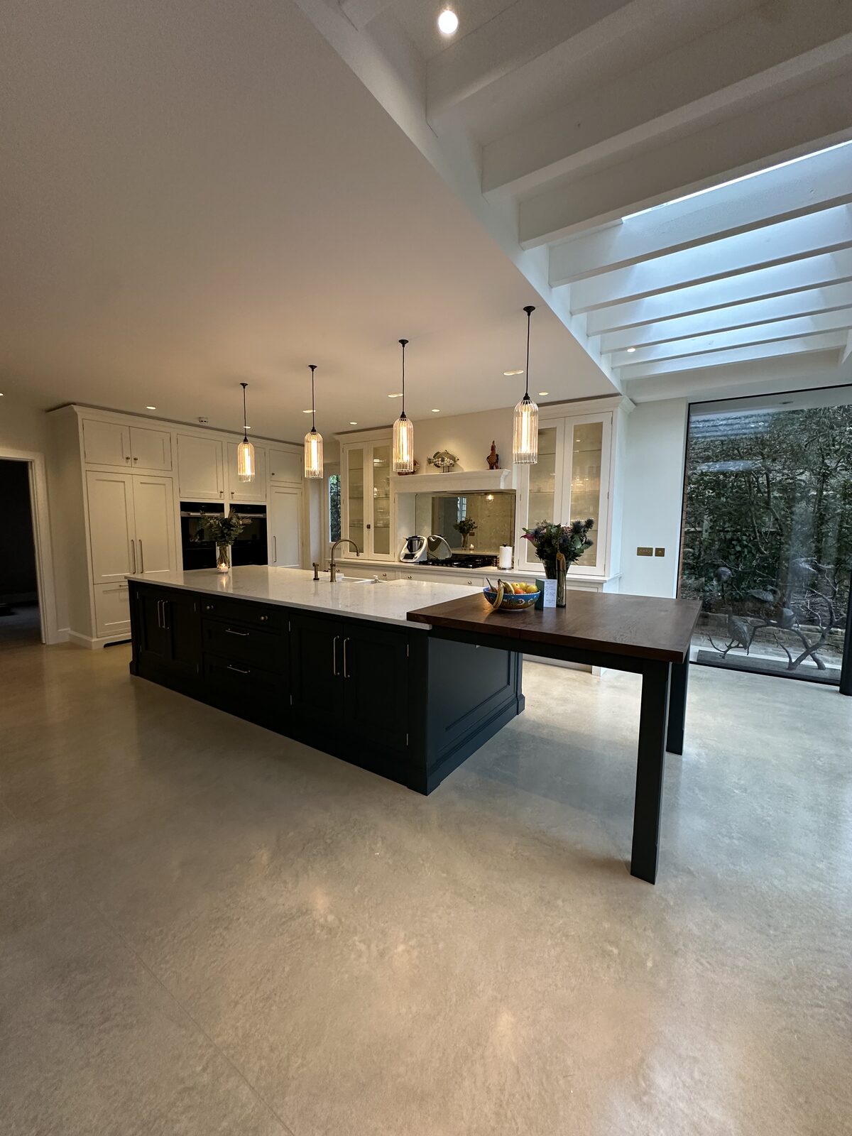 A calm, clutter-free kitchen with clear worktops, a large island and pendant lights