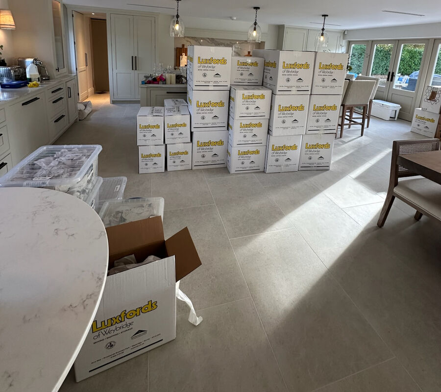 An open-plan kitchen on moving day, with removal boxes stacked across the floor