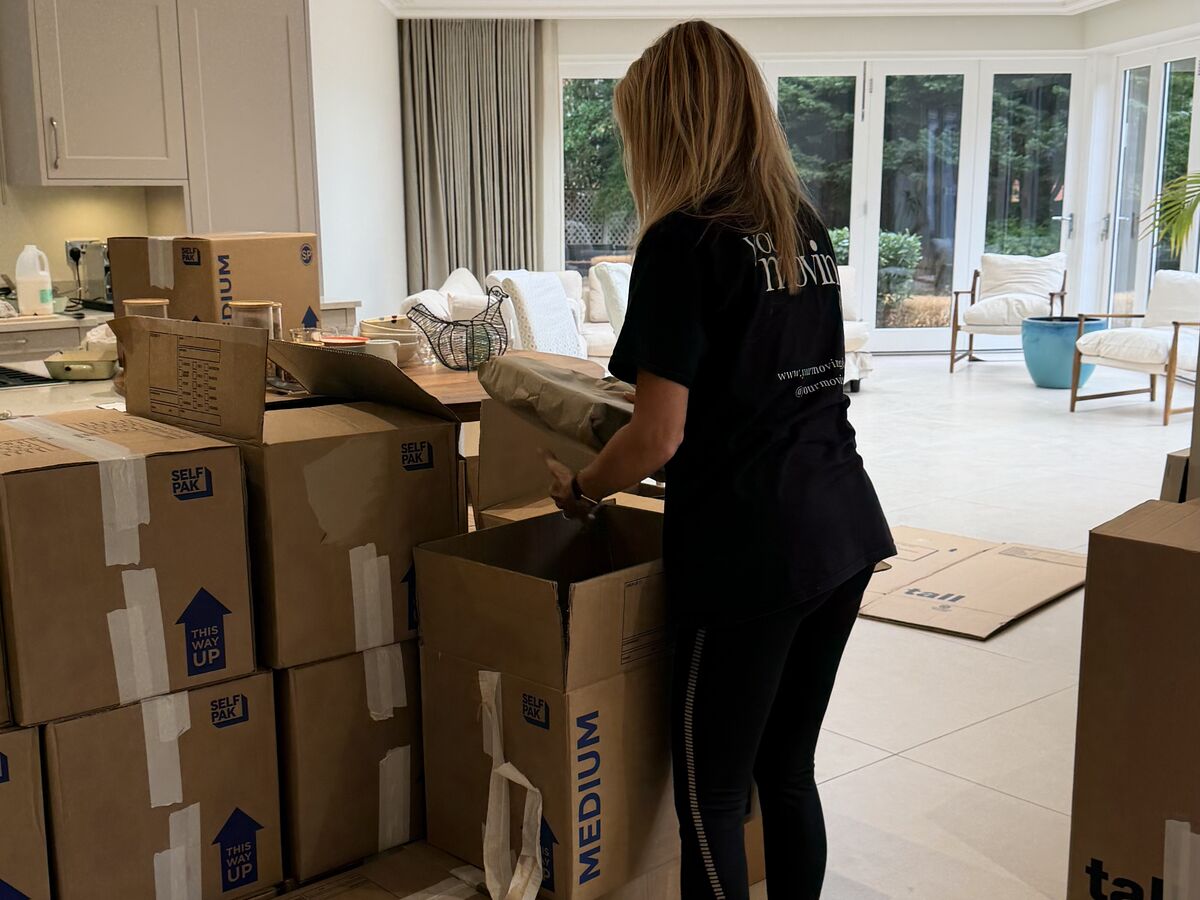 A Your Moving Day organiser in a branded T-shirt unpacking moving boxes in a bright open-plan kitchen